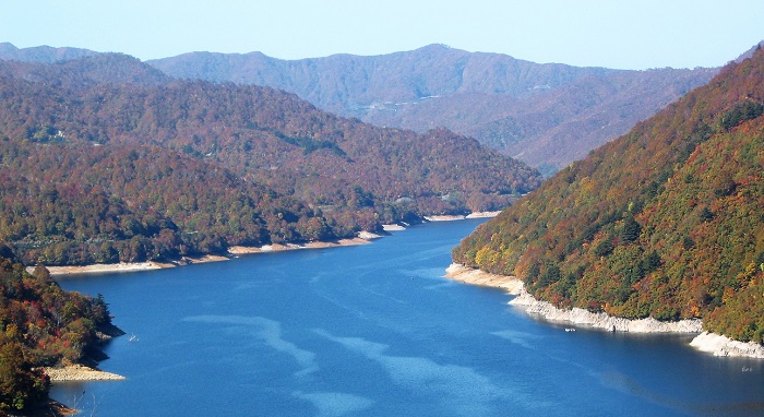 国道３５２号線より望む奥只見湖のマリンブルーの色合いと、深山霊峰の紅葉の姿です。画像の奥に国道の姿が見えますね。