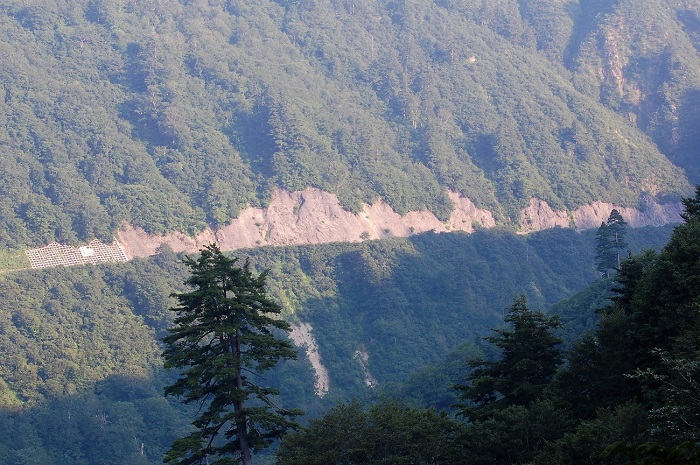 遠くに見る、険しい切り立った山々を貫く国道の景観は、奥只見の圧倒的な深山の秘境の光景です（２０１８年７月１９日）。