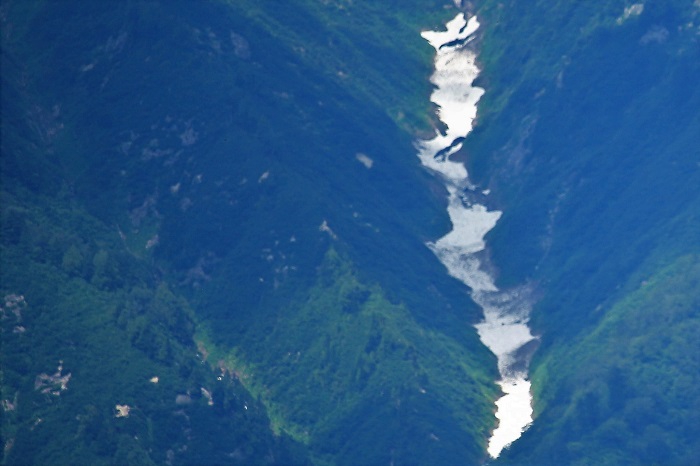 小沢平開墾地での作業に向かう途中、日本１００名山・平ヶ岳（標高２１４１ｍ）の万年雪の光景を遠方に見つめて。平ヶ岳の山容の大きさと雄大さと豪雪、そして大自然の素晴らしさと奥深さを改めて思った日々でした（２０２２年８月２日）。

