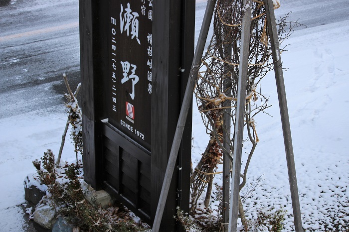 冬囲いに包まれた尾瀬野の看板。遠くからおいでいただき、御宿泊いただく御客様に、少しでもわかりやすいようにとの思いで作った看板ですが、冬期間、ほぼ半分は雪で埋まります（２０２２年１２月６日）。