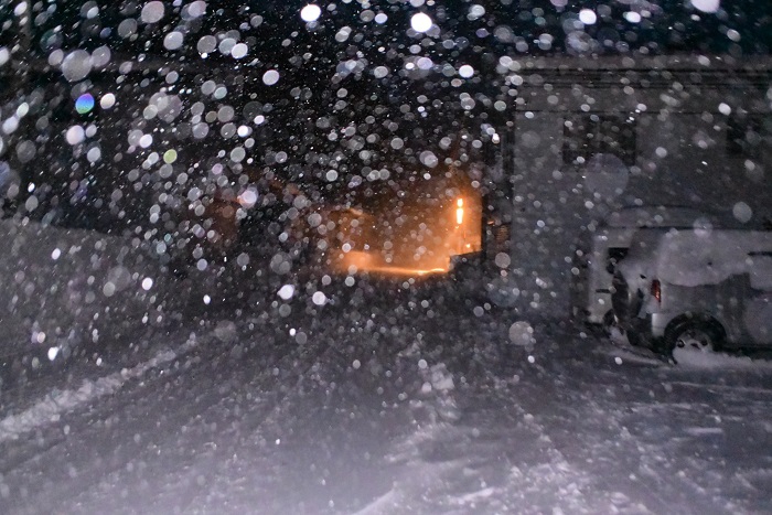 早朝の除雪作業を終えて。降りしきる雪の奥に街灯の明かりを遠くに望んで(2026年1月30日)。
